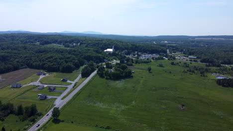 aerial view of a rural village surrounded by green fields and forests