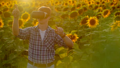 Der-Junge-Mann-Arbeitet-Mit-Einer-VR-Brille.-Er-Ist-In-Den-Arbeitsprozess-Eingebunden.-Es-Ist-Ein-Wunderschöner-Sonniger-Tag-Im-Sonnenblumenfeld