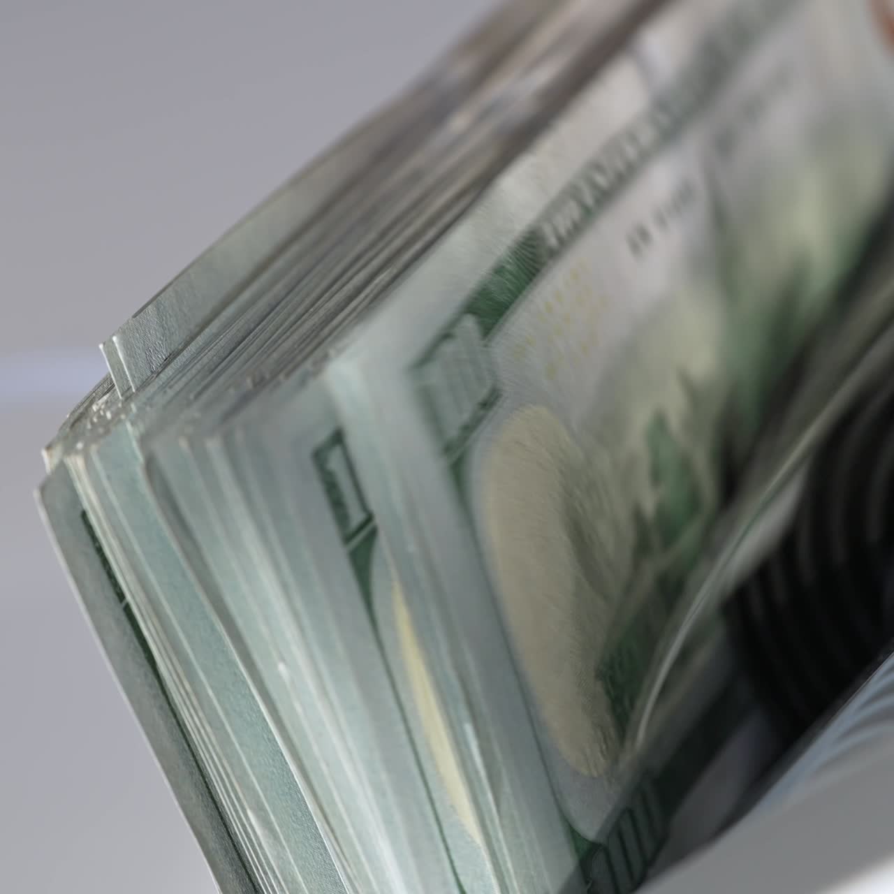 Pile of hundred dollar banknotes in the holder of cash machine. Close up. White background