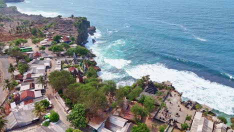 aerial view of coastal village with temple and ocean waves