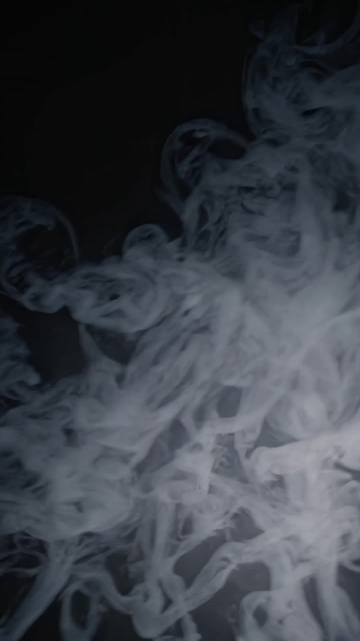 Concetto di video astratto di fumo vorticoso su sfondo scuro, catturato da una angolazione dal basso