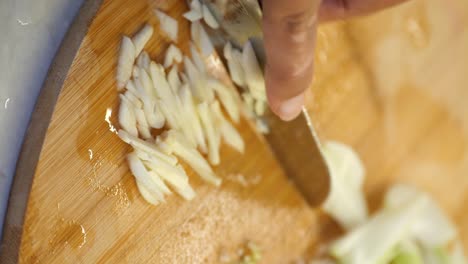 chopping garlic on a wooden cutting board