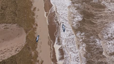 aerial view of a beach with windsurfing boards and powerful waves