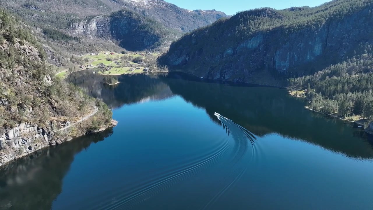 Barca che naviga su acque calme del fiordo vicino a Stamnes Vaksdal, Norvegia, con i riflessi delle montagne.