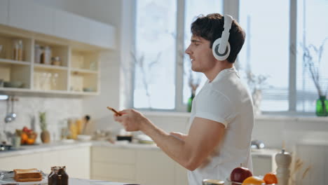 guy listening music kitchen in headphones close up. man dancing preparing toasts