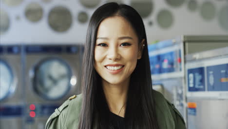 close up of beautiful young stylish woman smiling joyfully to camera in laundry service room