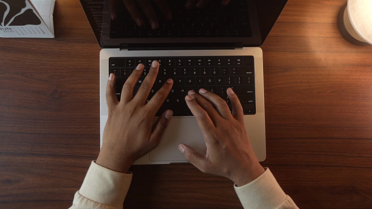 Mani che digitano sulla tastiera del laptop in una stanza calda, accogliente e illuminata