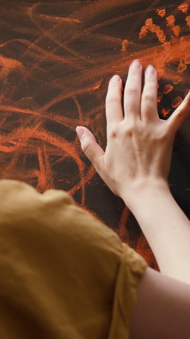 Artist's Hand Finger Painting Orange on Black Canvas