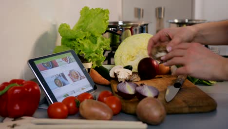 mujer joven desplazándose a través de recetas en su tableta en la cocina