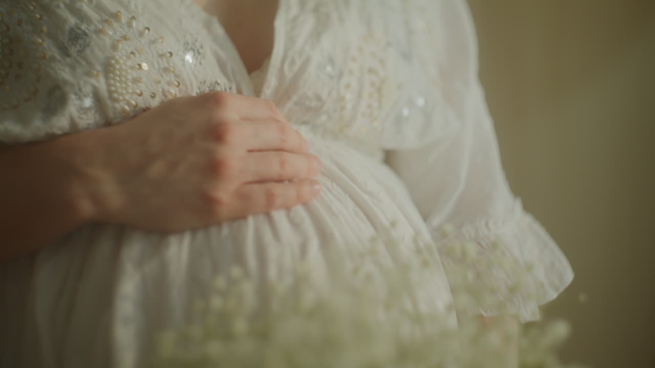 Donna incinta che abbraccia la pancia con un bouquet di gipsofila