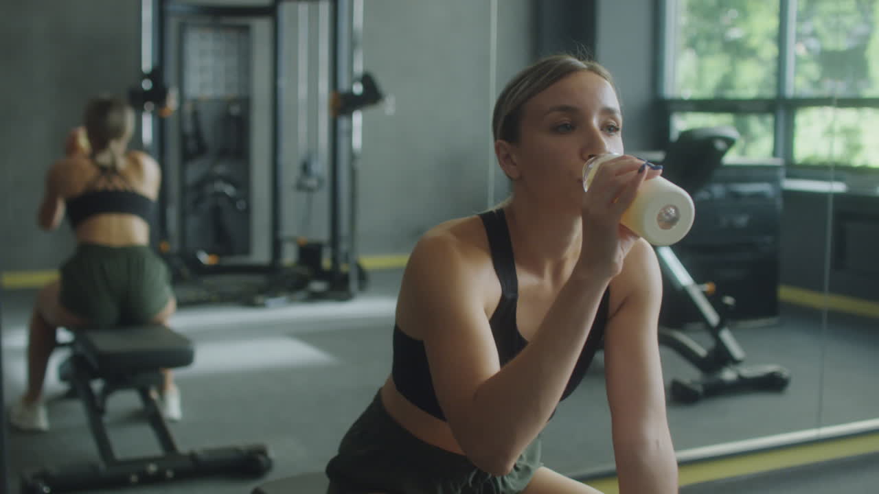 Woman Drinking Water and Resting in Gym