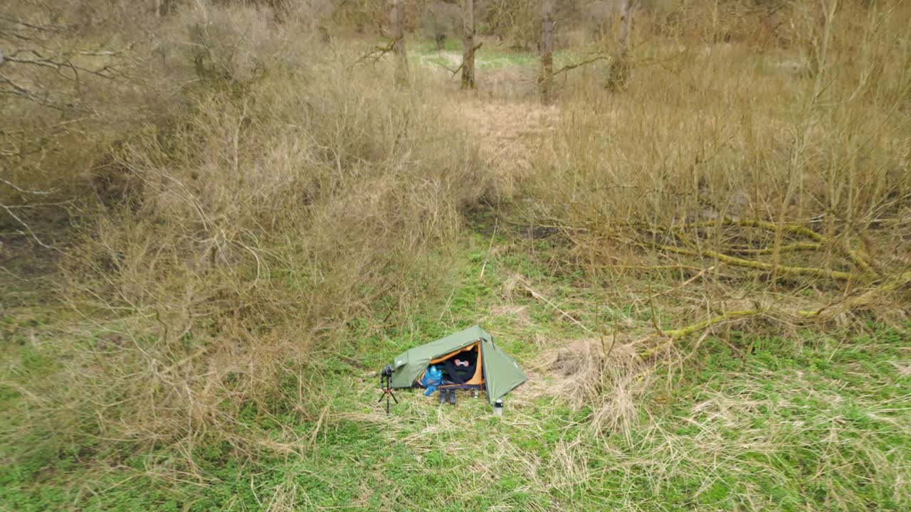 Mann sitter inne i campingtelt og flyr drone i Thetford Forest i Norfolk, Storbritannia