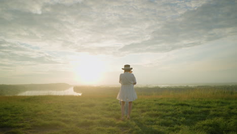 romantic couple spins on a grassy hill at sunset by a serene lake, man in white shirt and hat, woman in flowing white dress, embracing each other in a tender moment of love, warmth, and connection