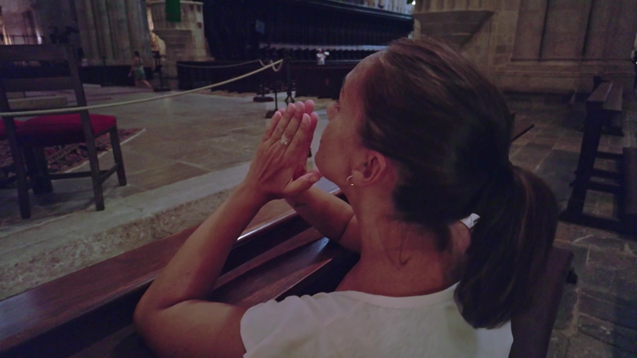 Donna religiosa che prega in ginocchio in una chiesa o cattedrale