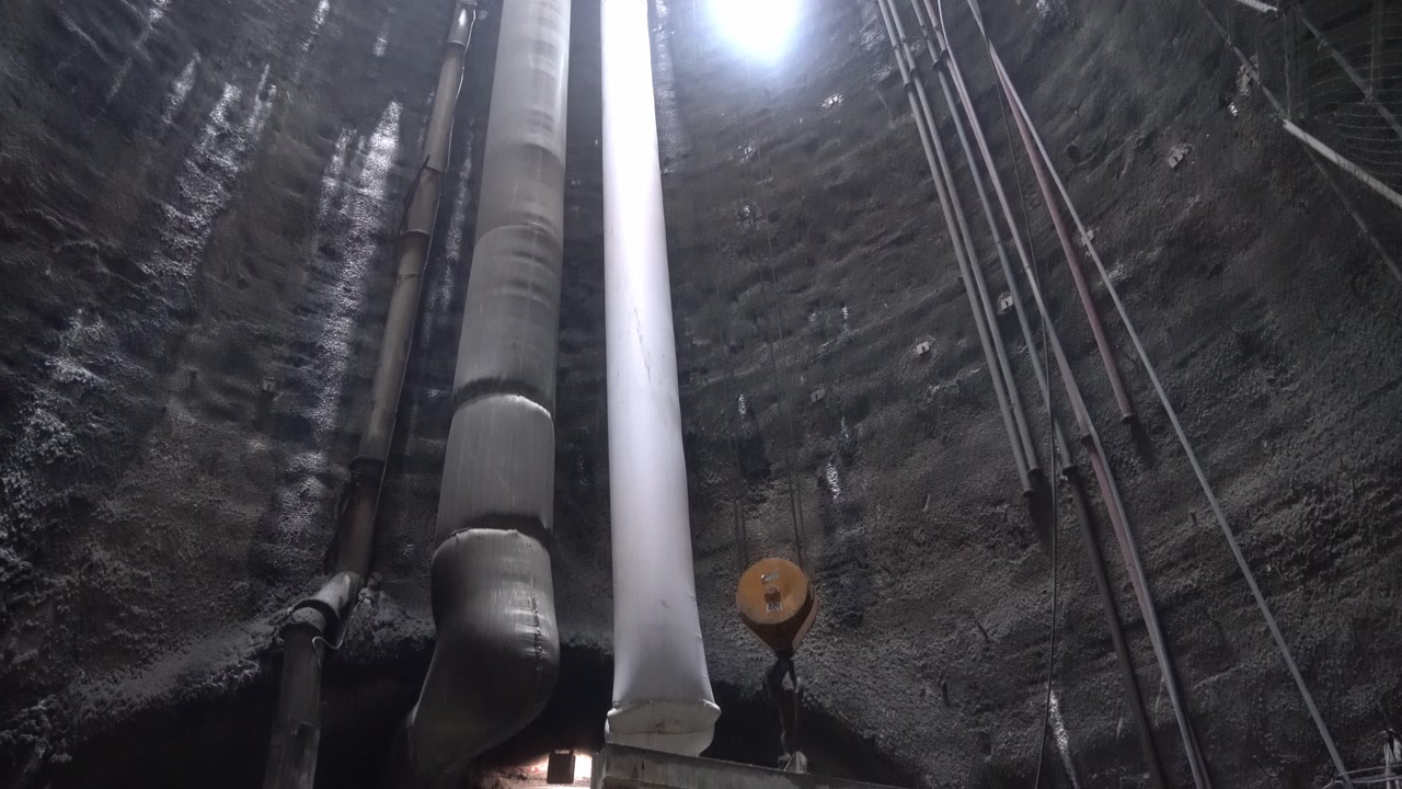 The process of filling the crane bucket with excavation material removed by an excavator in an underground tunnel project to be carried to the surface via a shaft. Heavy industry.