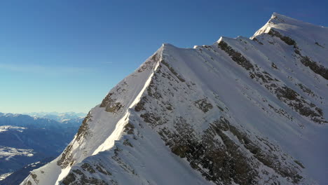 vista aérea que sube por una cresta de montaña en los alpes franceses en invierno con sol