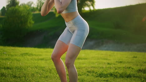 una mujer en cuclillas con pesas en el parque al atardecer realizando estocadas hacia el lado. motivación y entrenamiento deportivo. una mujer soltera hace ejercicios al atardecer en el verano