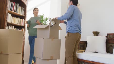 video of happy diverse couple unpacking boxes after moving in