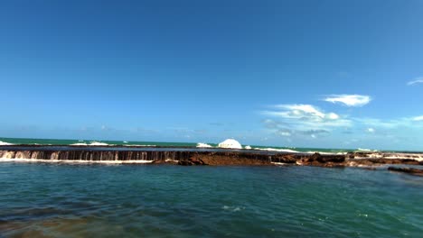 Beautiful-tilt-up-shot-of-a-natural-waterfall-in-the-ocean-created-low-tide-in-the-small-beach-town-of-Sibauma-near-Pipa-in-Rio-Grande-do-Norte,-Brazil