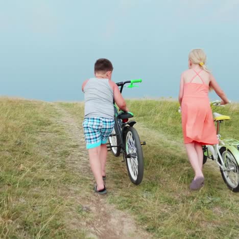 Zwei-Kinder-Fahren-Mit-Ihren-Fahrrädern-Den-Hügel-Hinauf