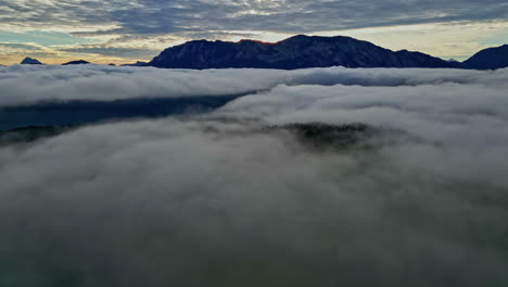 panorama of sea of clouds covering mountains on cloudy sunset