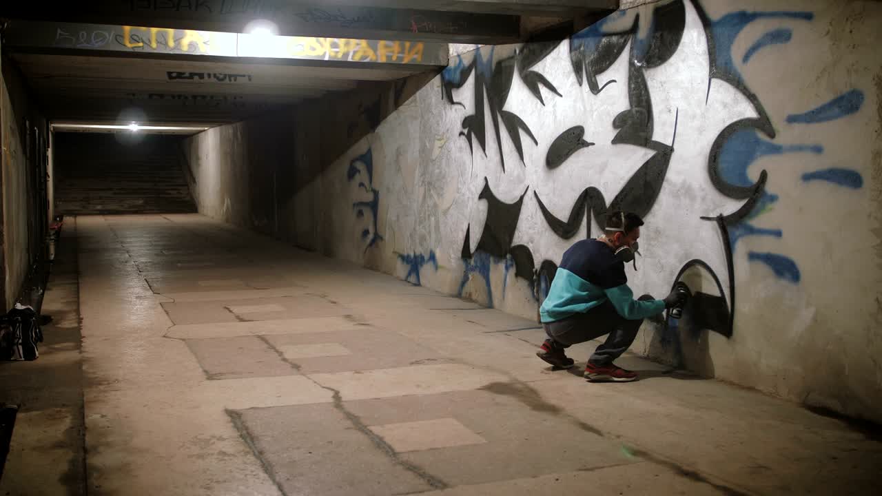 Graffitaro che dipinge sul muro della metropolitana