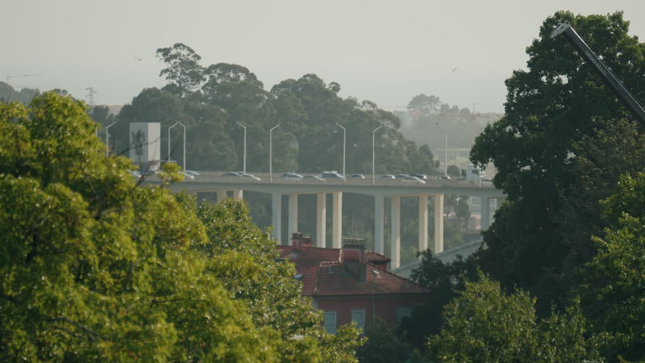 cars crossing Ponte da Arrábida bridge in Porto Portugal with lush trees in the foreground