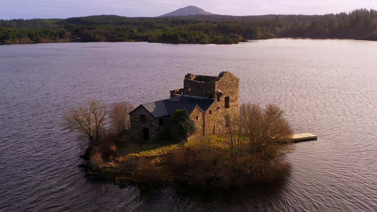Static shot of O'Flaherty Tower House bathed in warm sunset light over the lake