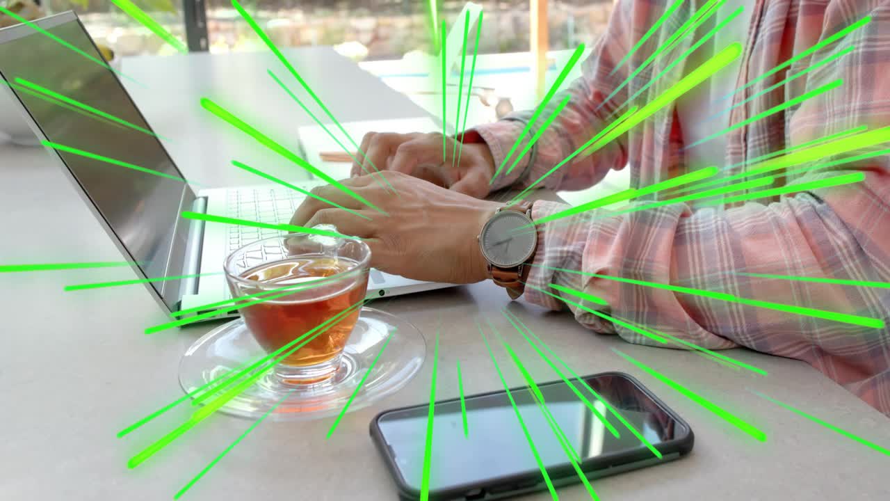 Man at window starting typing on laptop for work, green radial streaks emphasizing hands and teacup