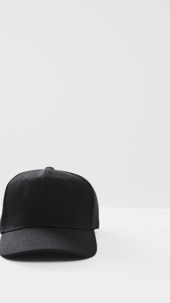 Vertical video of black baseball cap and copy space on white background