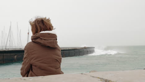 Einsamer-Junge,-Der-An-Der-Küste-Sitzt-Und-Auf-Das-Meer-Blickt