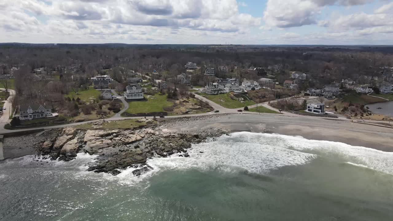 Vista statica da drone delle onde che si infrangono sulle rive di una spiaggia di sabbia e roccia nera
