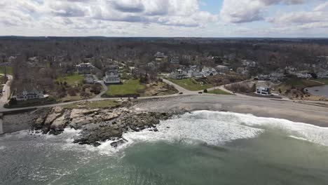 static drone view of waves crashing upon the shores of a black rock and sand beach