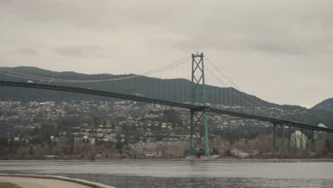 wide panning shot of lions gate bridge and man running in stanley park