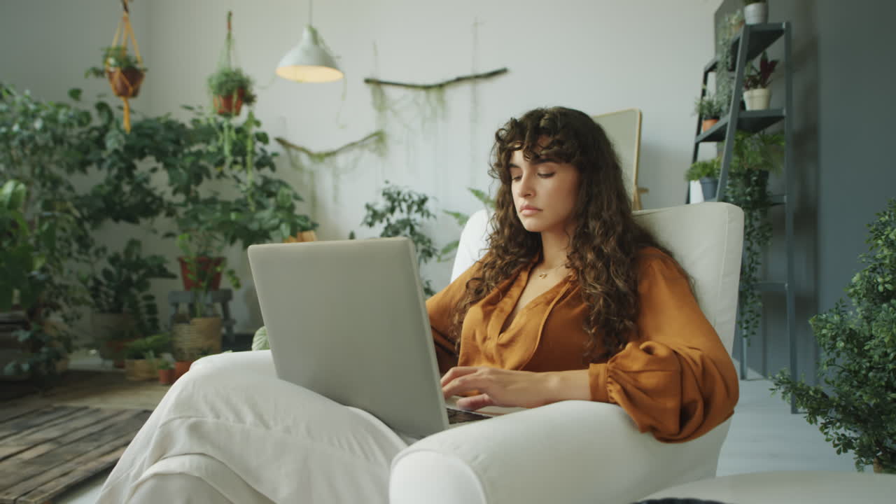 Woman Working on Laptop in Room with Plants
