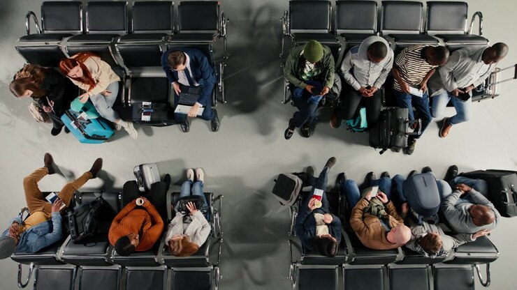 Tourists in airport lounge boarding for departing airplane flights, standing up