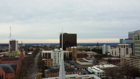 A-drone-shot-of-a-white-cross-on-a-steeple-with-the-Comubia-state-capital-building-in-the-background