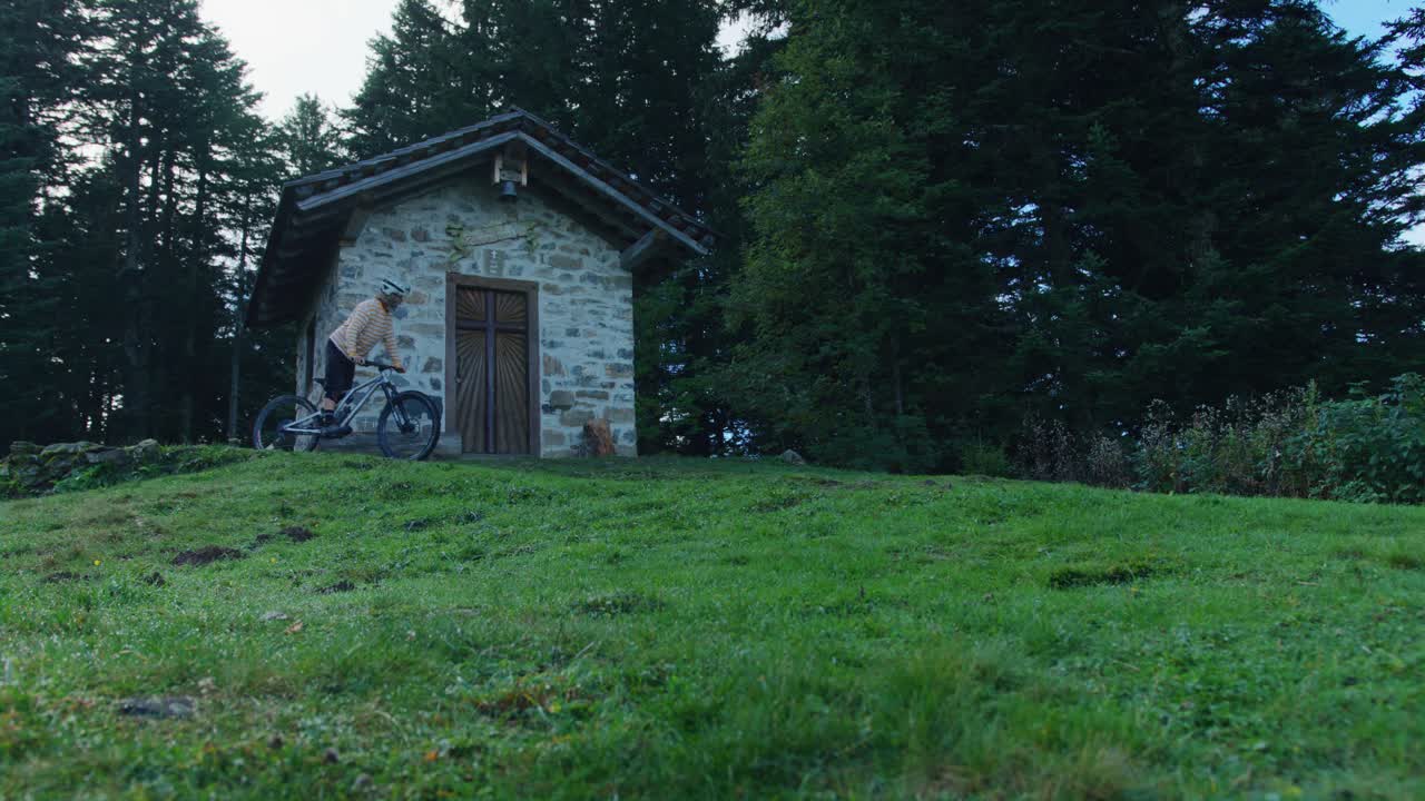 자전거 타는 사람이 예배당에 다가가서 들어가려고 멈춥니다.