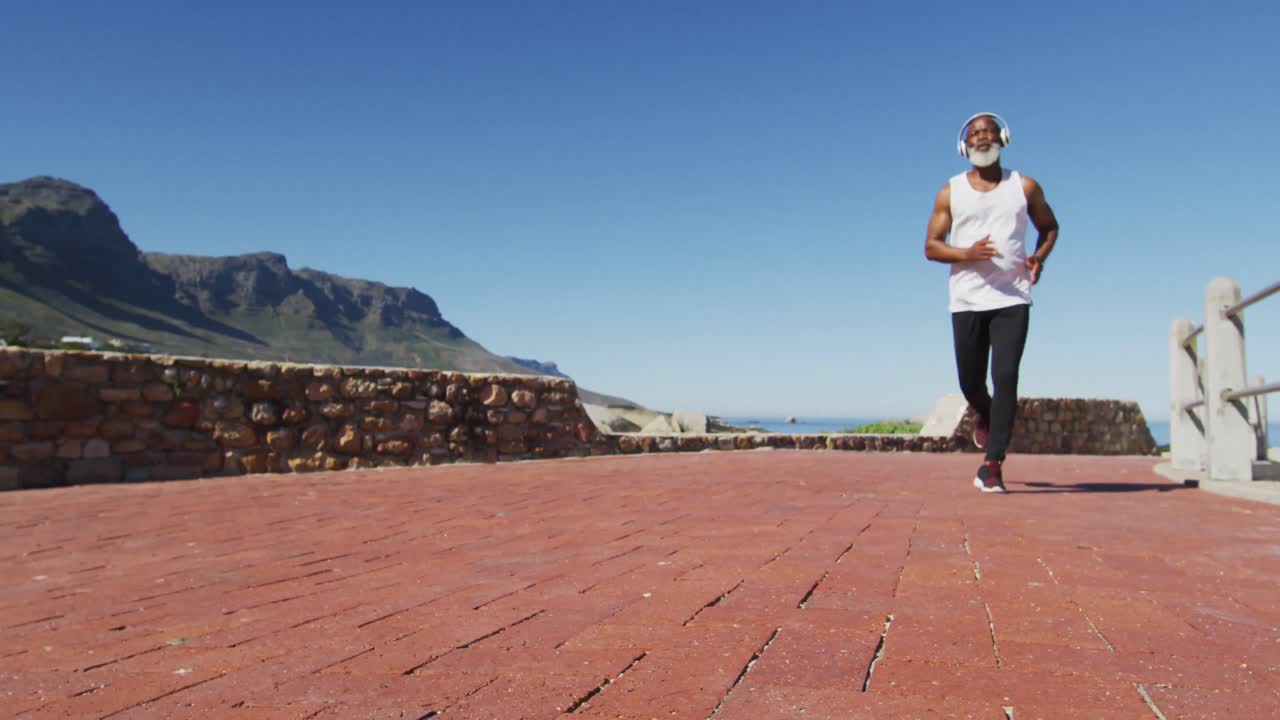 hombre afroamericano senior haciendo ejercicio corriendo en la carretera junto al mar
