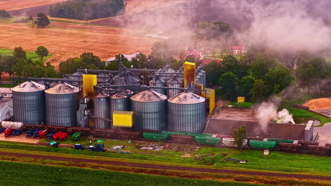 Ländliche Agrarsilos mit aufsteigendem Dampf über grünen Feldern Panorama