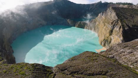 aerial establishing shot of the vapor in the volcanic crater of mount kelimutu at flores island, indonesia