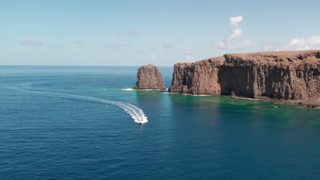 roque partido, gran canaria: aerial view of an approaching boat with roque partido in the background on a sunny day