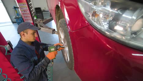 mecánico de automóviles reemplazando un neumático de automóvil en un taller de garaje. cámara lenta. servicio de automóviles