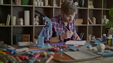 Designer-working-on-sketch-of-leather-product-at-home.-Leather-man-thinking
