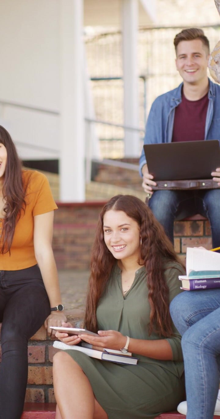 Gruppo eterogeneo di studenti che studiano insieme sui gradini del campus