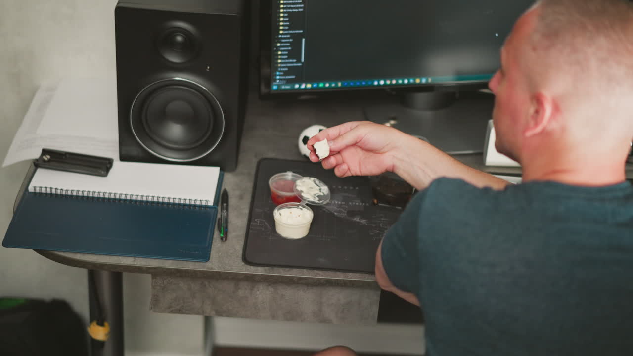 Person Eating Dessert at a Computer Desk