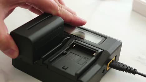 cerrar la mano del hombre instalando la batería en el cargador negro con pantalla led