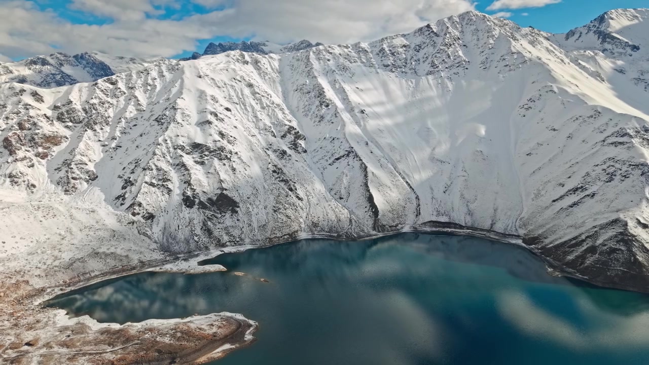 Luftfoto i kredsløb, der viser et gigantisk sneklædt bjerg ved El Yeso-reservoiret på en solrig dag, Cajon del Maipo, Chile