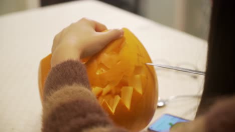 lady making the final touches of carving and cutting a pumpkin on halloween