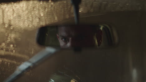 man looking in car mirror at night